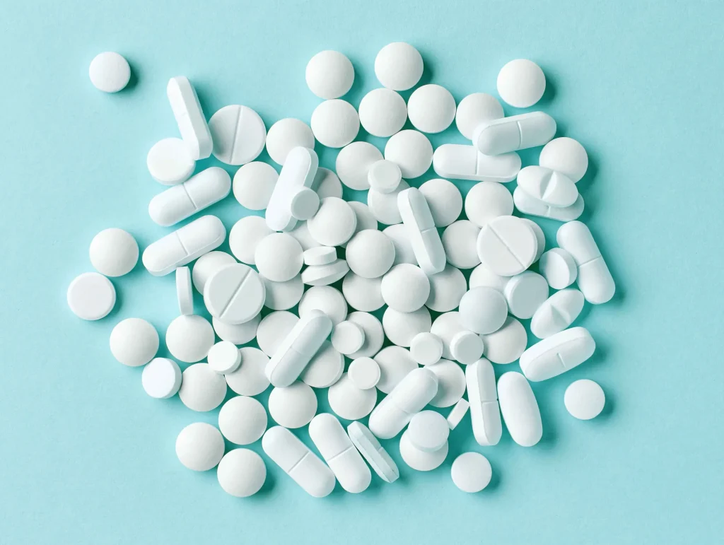 A pile of white pills of various shapes and sizes.