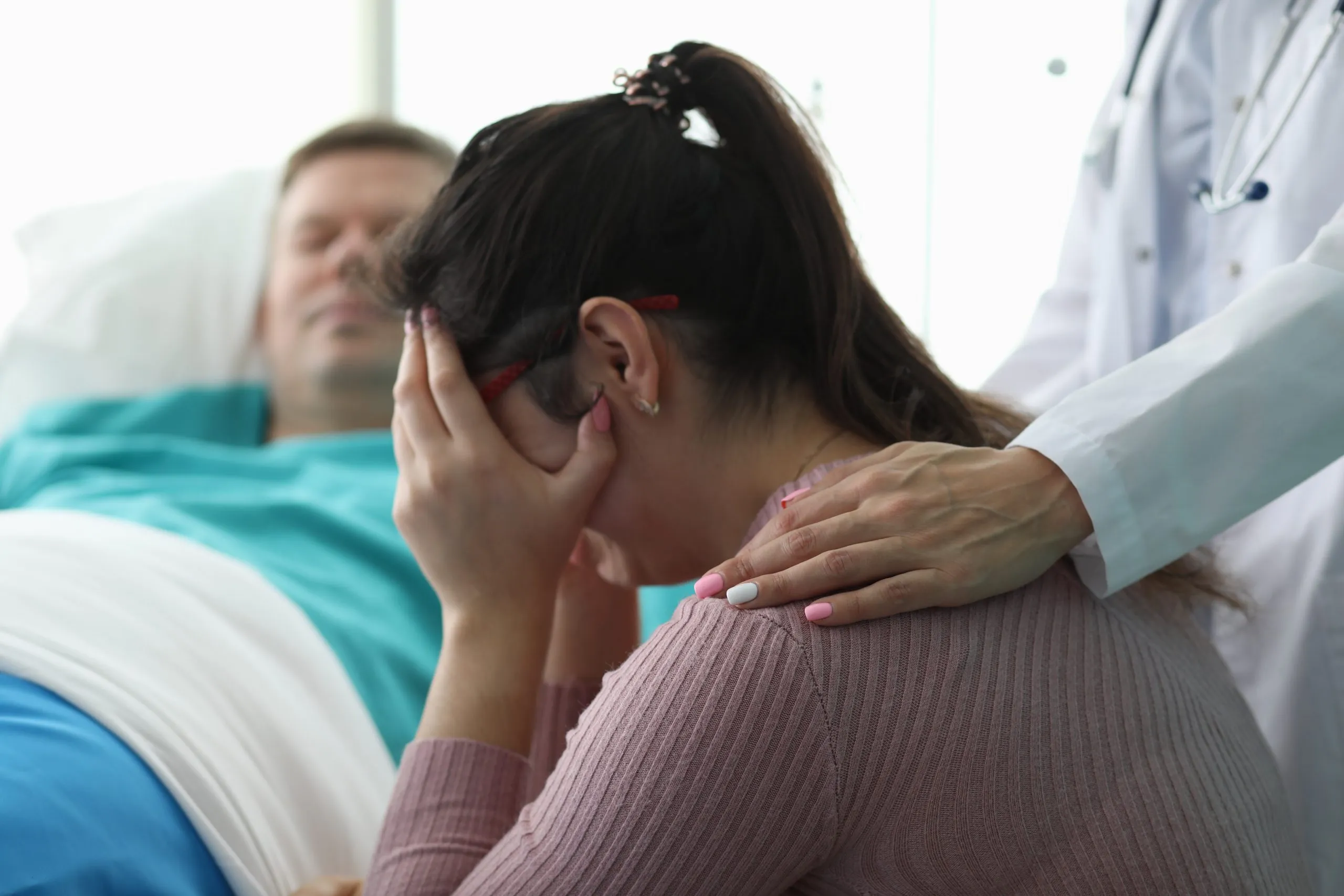 Woman crying in front of man in hospital bed after injury by medical malpractice. If you’ve been injured by a medical professional, speak to a medical malpractice lawyer. 
