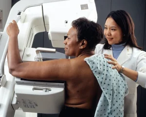 Woman receiving a mammogram alongside technician