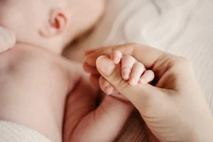 A mom holding her little baby's hand after childbirth. If your baby sustained a shoulder dystocia birth injury our birth injury attorney in Baltimore has the skills required to help seek compensation.