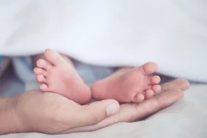 Mom holding newborn baby feet. If you or your infant have suffered an injury due to negligent medical staff, our birth injury lawyers are here to help.