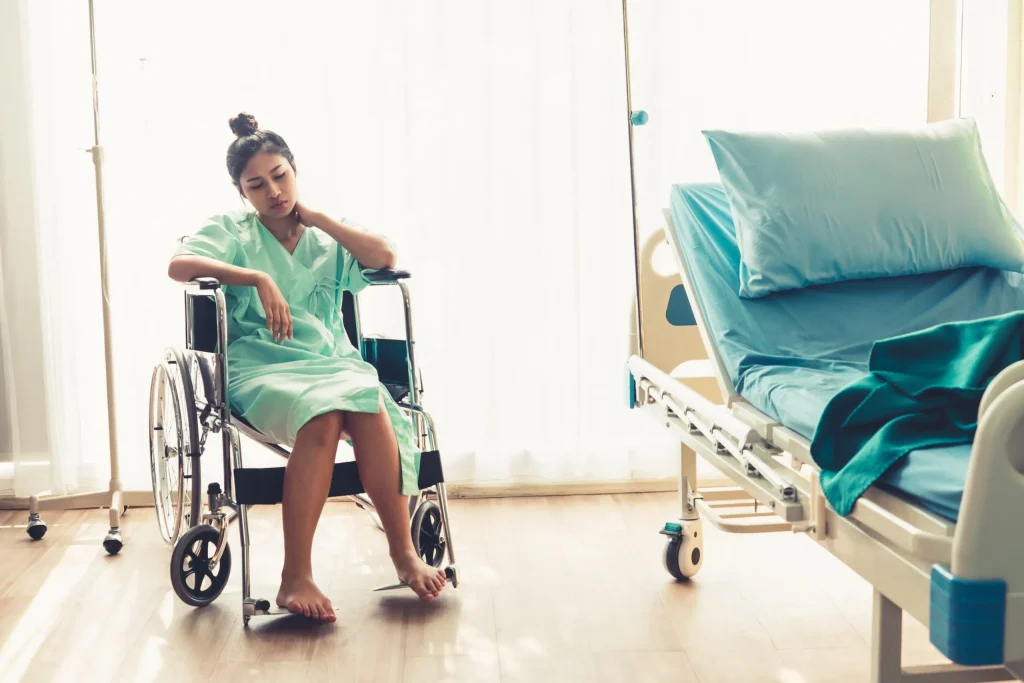 A female patient sitting in a wheelchair next to a hospital bed, in pain after becoming the victim of negligence from a medical professional. Our Overlea medical malpractice lawyer can help navigate the process of pursuing justice for your injury.